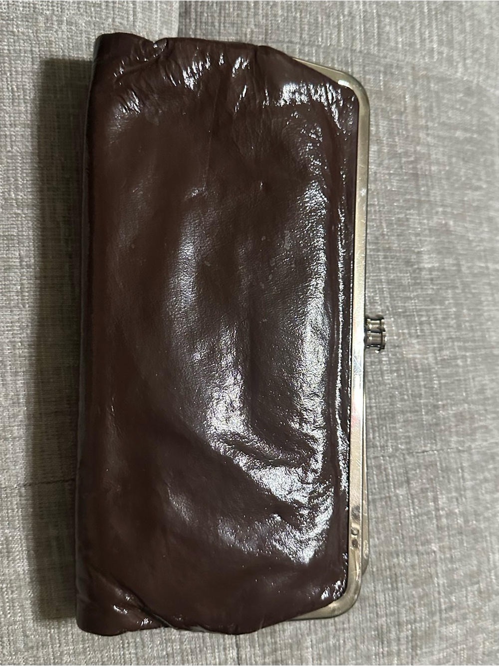 Brown patent leather double frame clutch wallet by HOBO international.